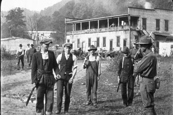 Three miners with a federal soldier prepare to surrender their weapons