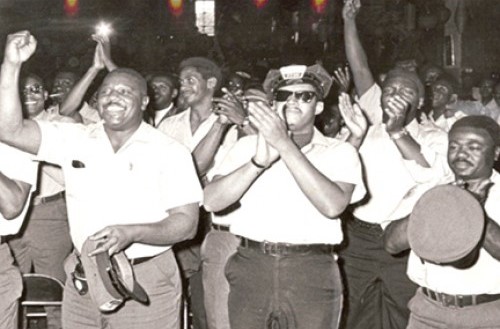 A still from the documentary "Labor Beat: CTA Strike of 1968" showing a group of black bus drivers applauding and cheering