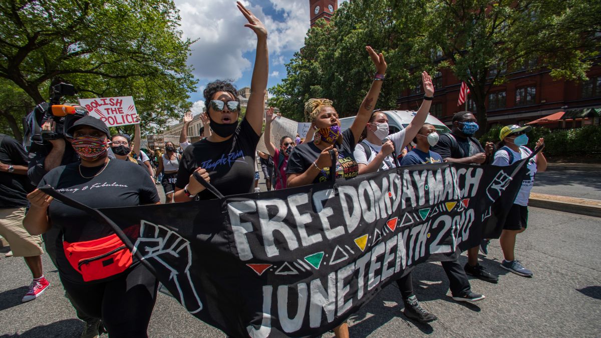 Protesters march towards the Martin Luther King Jr. Memorial in Washington on Friday, June 19th, 2020. A banner is displayed, reading "FREEDOM DAY MARCH 2020", another sign reads "ABOLISH THE POLICE" [CNN]